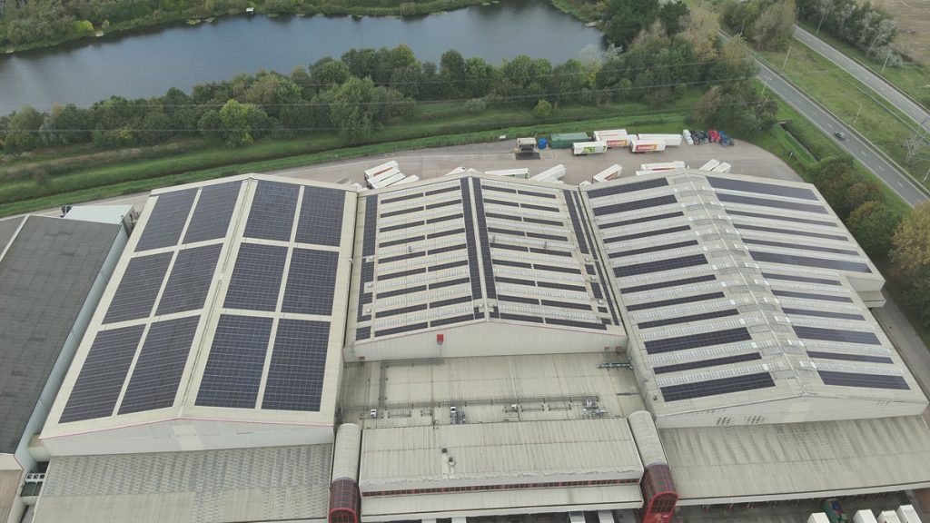 Aerial view of a large Iceland warehouse featuring Ortus Energy rooftop solar panels, showcasing sustainable energy solutions.
