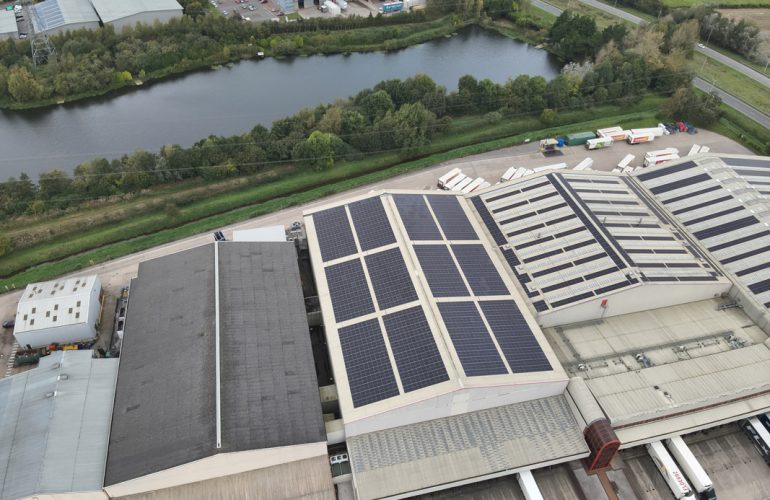 Aerial view of a large Iceland warehouse featuring Ortus Energy rooftop solar panels, showcasing sustainable energy solutions.