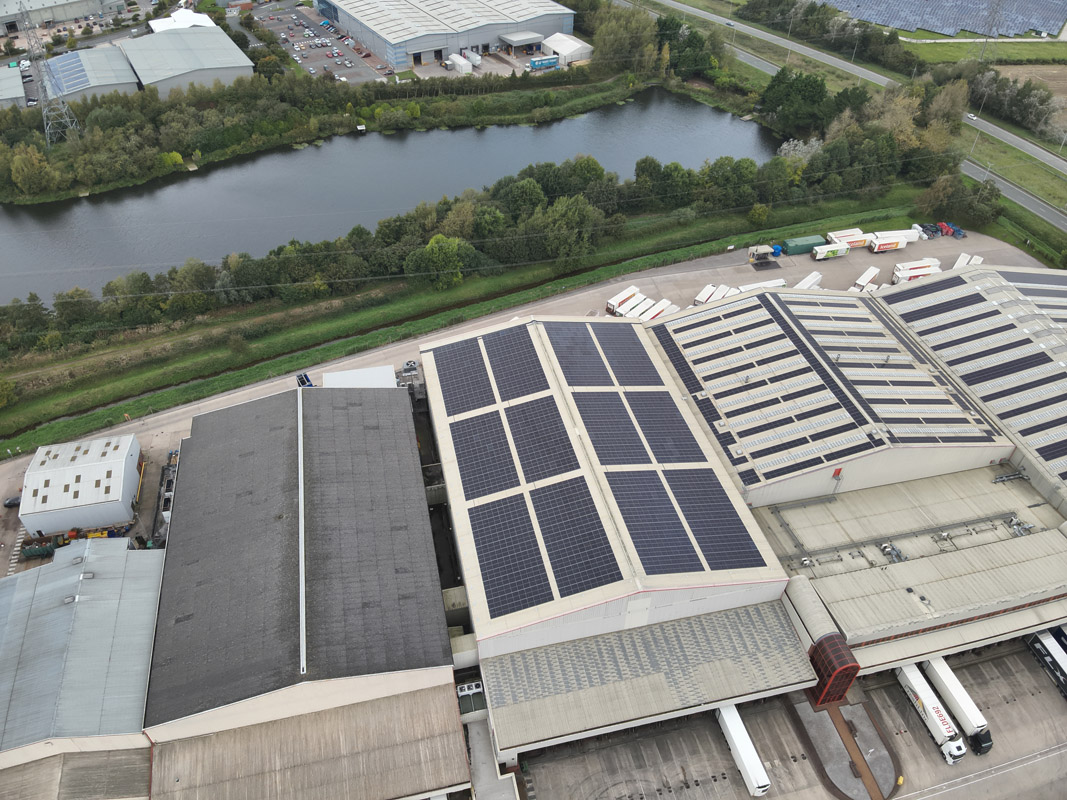 Aerial view of a large Iceland warehouse featuring Ortus Energy rooftop solar panels, showcasing sustainable energy solutions.