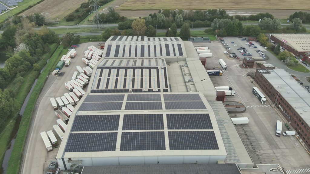 Aerial view of a large Iceland warehouse featuring Ortus Energy rooftop solar panels, showcasing sustainable energy solutions.