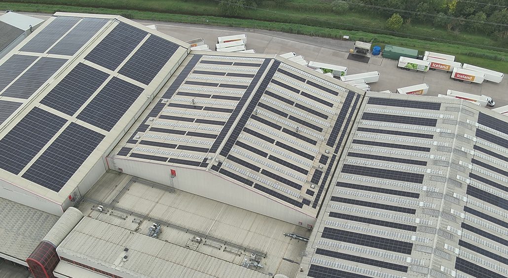 Aerial view of a large Iceland warehouse featuring Ortus Energy rooftop solar panels, showcasing sustainable energy solutions.